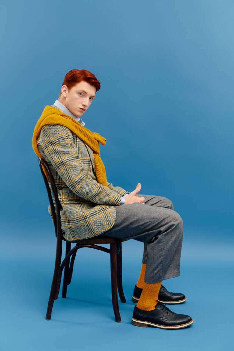 A young man with striking red hair showcases a layered winter outfit, exuding style and confidence